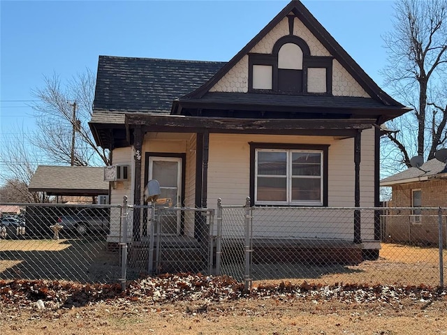 view of front of home featuring a fenced front yard, a shingled roof, covered porch, a gate, and an attached carport