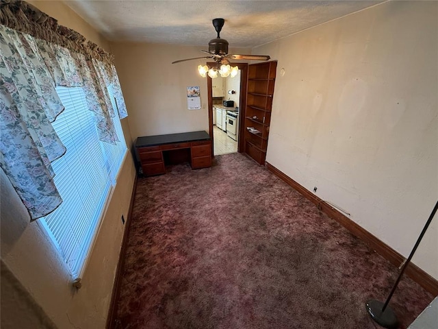 interior space with dark carpet, a ceiling fan, and baseboards