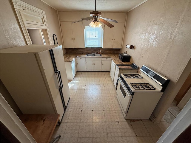 kitchen with white appliances, white cabinets, light floors, and a textured wall