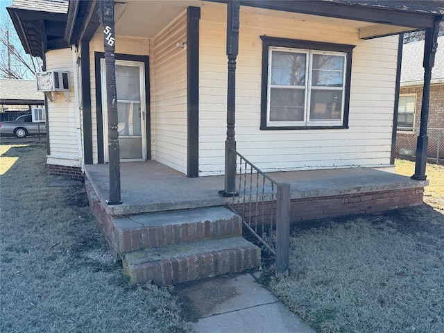 view of exterior entry with a carport, cooling unit, and covered porch