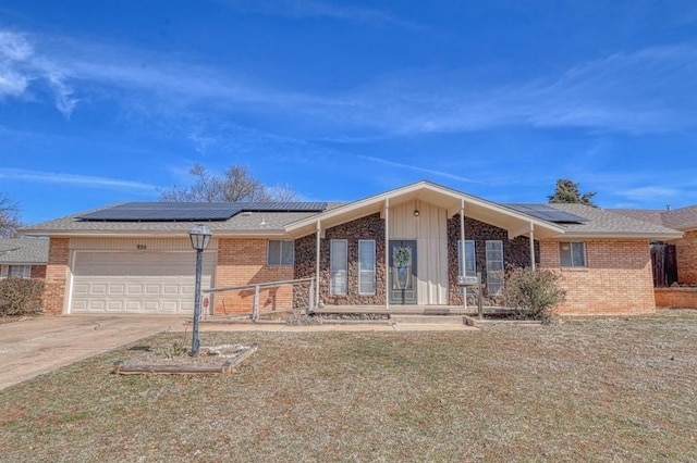 view of front of house featuring a garage, concrete driveway, brick siding, and a front yard