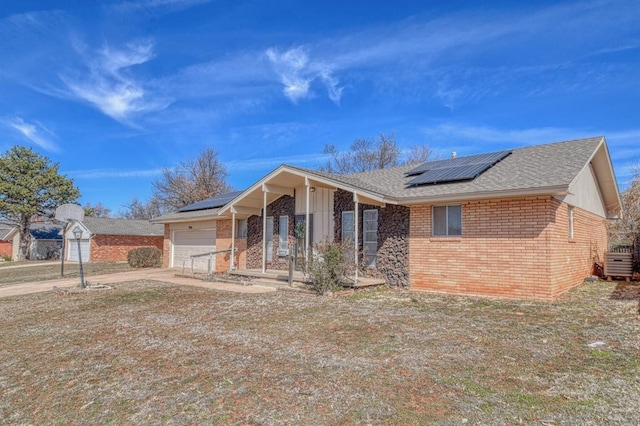 view of front of property with a porch, an attached garage, brick siding, driveway, and roof mounted solar panels