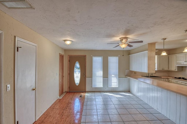 foyer with a textured ceiling, ceiling fan, light tile patterned flooring, and visible vents