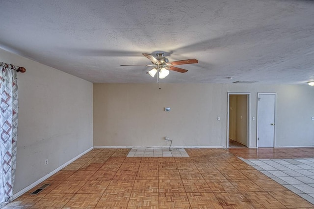 spare room with a ceiling fan, visible vents, a textured ceiling, and baseboards