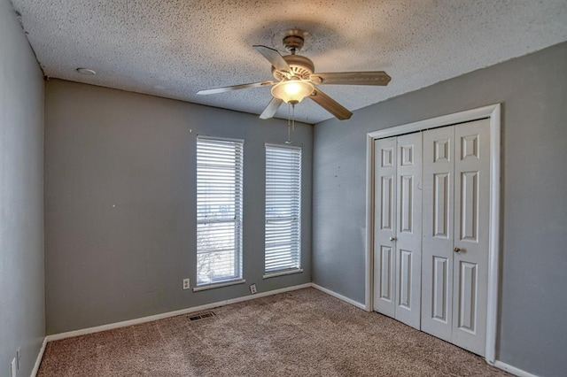 unfurnished bedroom featuring a textured ceiling, visible vents, a closet, and light colored carpet