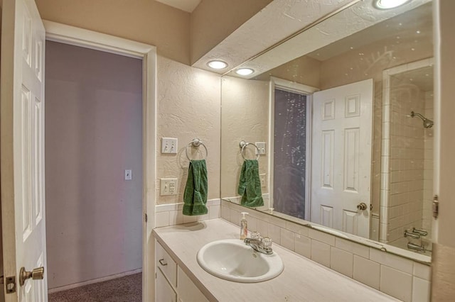 full bath with washtub / shower combination, a textured wall, and vanity