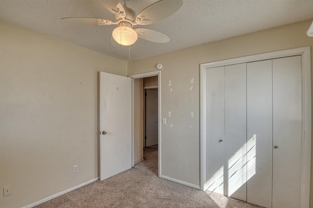 unfurnished bedroom with ceiling fan, a textured ceiling, light colored carpet, baseboards, and a closet