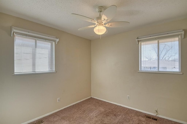 unfurnished room featuring a textured ceiling, a ceiling fan, visible vents, baseboards, and carpet