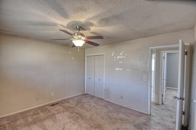 unfurnished bedroom featuring a closet, light colored carpet, visible vents, a ceiling fan, and a textured ceiling