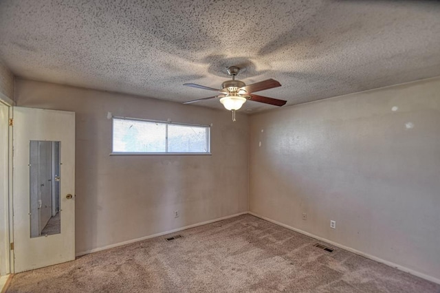 carpeted empty room with a ceiling fan, visible vents, a textured ceiling, and baseboards