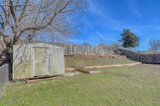 view of yard with a shed, an outdoor structure, a fenced backyard, and a vegetable garden