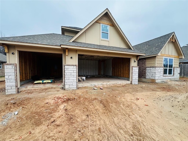 view of front of property featuring stone siding and roof with shingles