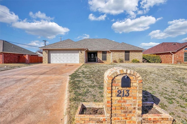 single story home with a garage, brick siding, driveway, and a front lawn