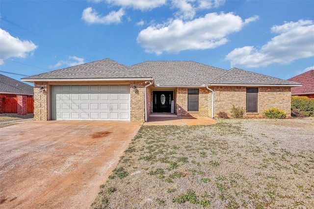 ranch-style house with a garage, driveway, a shingled roof, and brick siding