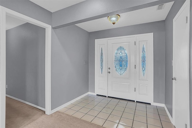 entrance foyer with light tile patterned floors, light colored carpet, visible vents, and baseboards