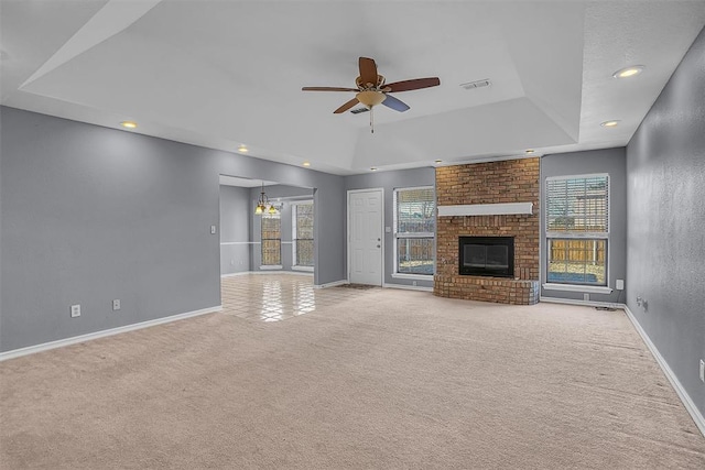 unfurnished living room with baseboards, a fireplace, a tray ceiling, and carpet flooring