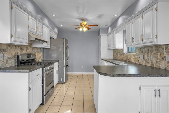 kitchen featuring dark countertops, gas range, under cabinet range hood, and white cabinets