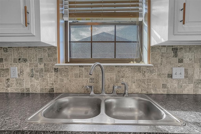 kitchen featuring dark countertops, a healthy amount of sunlight, white cabinetry, and a sink