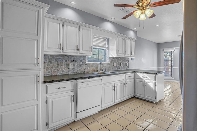 kitchen with dark countertops, white cabinetry, dishwasher, and a peninsula