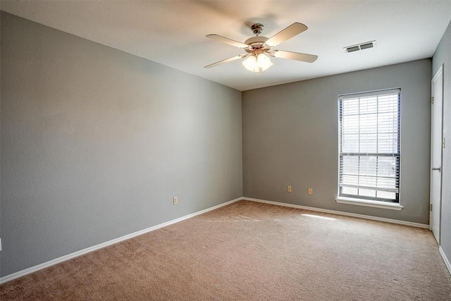 empty room with light carpet, baseboards, visible vents, and a ceiling fan