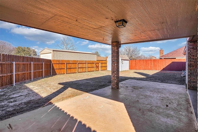 view of yard with a patio area, a fenced backyard, an outdoor structure, and a storage shed