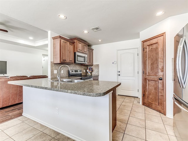 kitchen with light tile patterned floors, visible vents, open floor plan, stainless steel appliances, and a sink