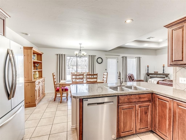 kitchen featuring light tile patterned floors, dishwasher, freestanding refrigerator, a tray ceiling, and a sink