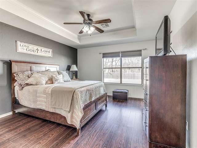 bedroom featuring baseboards, visible vents, ornamental molding, dark wood-style flooring, and a tray ceiling