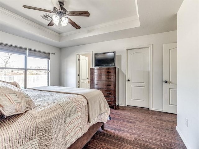 bedroom with visible vents, baseboards, ornamental molding, dark wood-style floors, and a tray ceiling