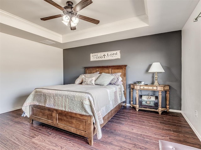 bedroom featuring baseboards, a raised ceiling, ceiling fan, ornamental molding, and wood finished floors