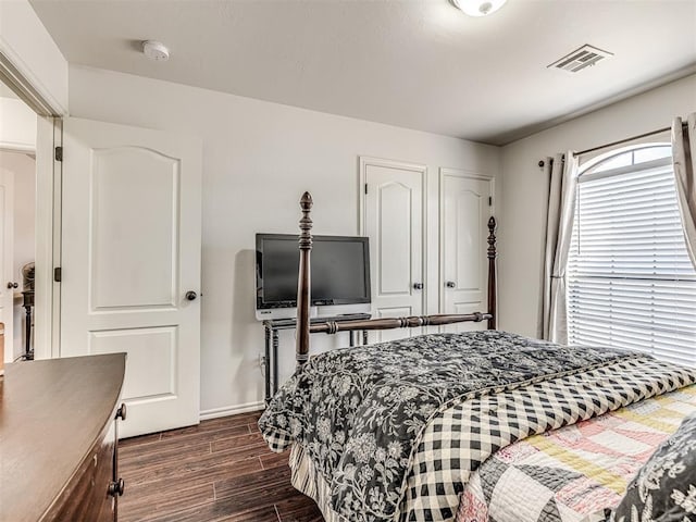 bedroom with baseboards, visible vents, and dark wood finished floors