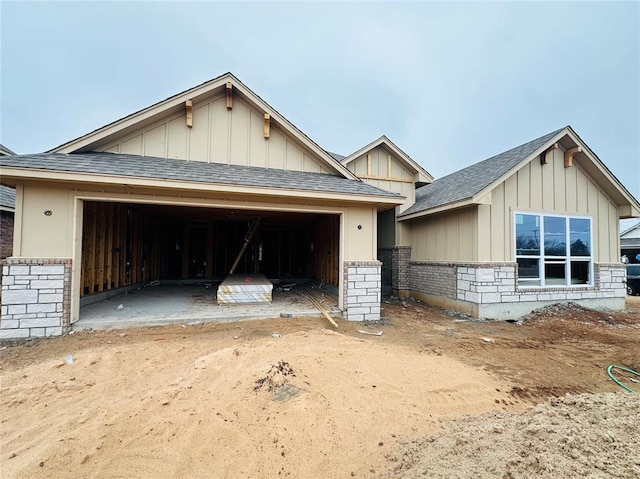 view of front of home featuring an attached garage, a shingled roof, board and batten siding, and brick siding