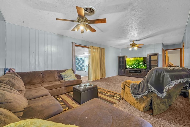 living area with carpet floors, ceiling fan, visible vents, and a textured ceiling