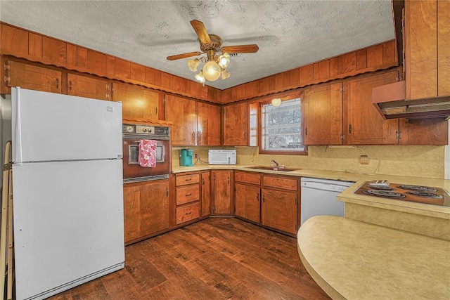 kitchen featuring light countertops, white appliances, dark wood-style flooring, and brown cabinetry