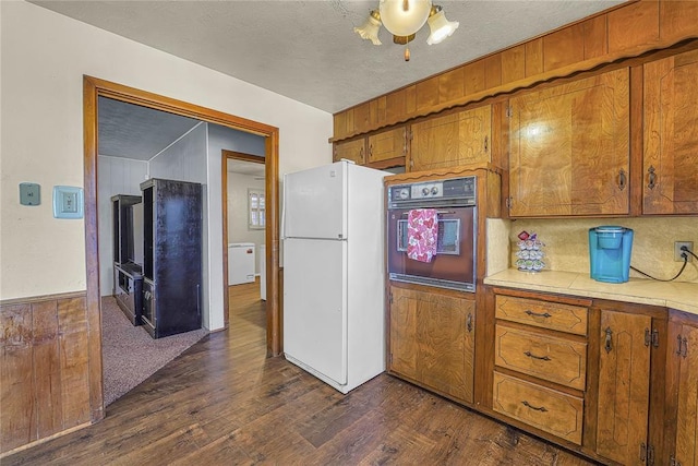 kitchen featuring light countertops, wall oven, freestanding refrigerator, and brown cabinets