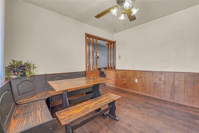 dining room with wood-type flooring, wainscoting, ceiling fan, and wood walls