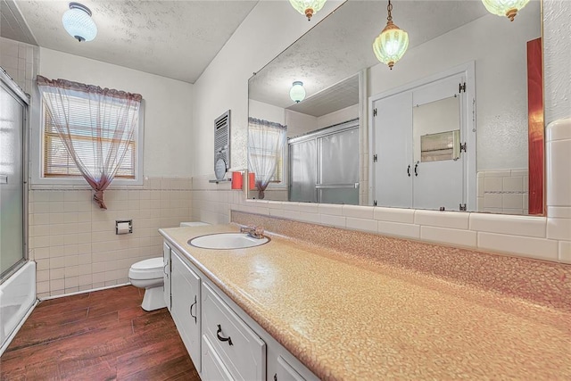 full bath with tile walls, toilet, vanity, a textured ceiling, and wood finished floors