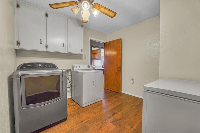 washroom featuring cabinet space, baseboards, ceiling fan, dark wood-style flooring, and washing machine and dryer