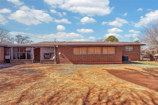 back of house featuring brick siding and a sunroom