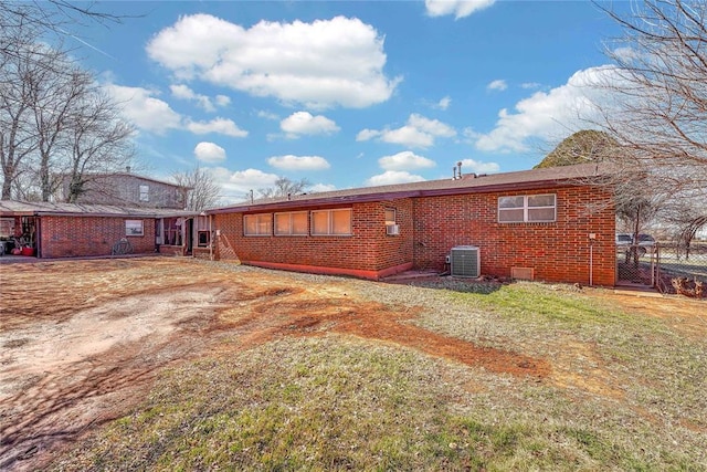 back of house featuring brick siding and a lawn