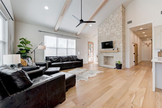 living room with a fireplace, visible vents, high vaulted ceiling, light wood-type flooring, and beamed ceiling