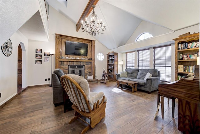 living area featuring arched walkways, high vaulted ceiling, wood finished floors, baseboards, and a brick fireplace