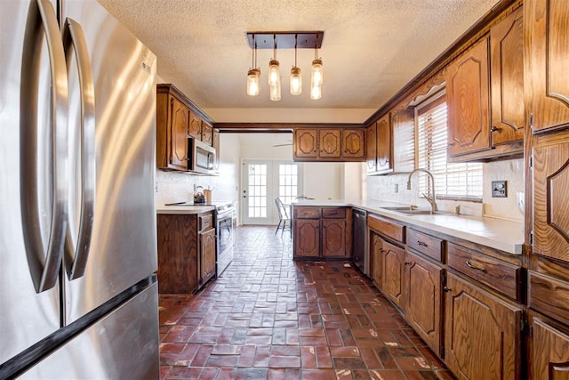 kitchen with brown cabinets, stainless steel appliances, light countertops, pendant lighting, and backsplash