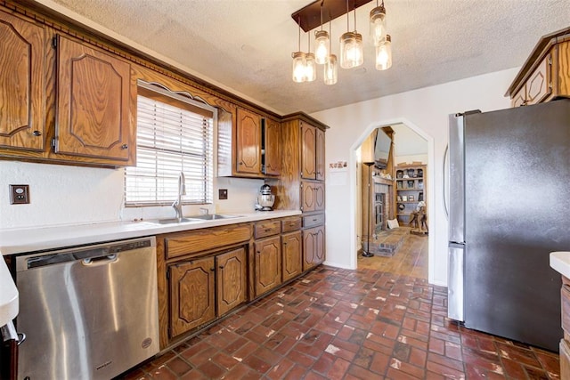 kitchen with arched walkways, light countertops, appliances with stainless steel finishes, and pendant lighting