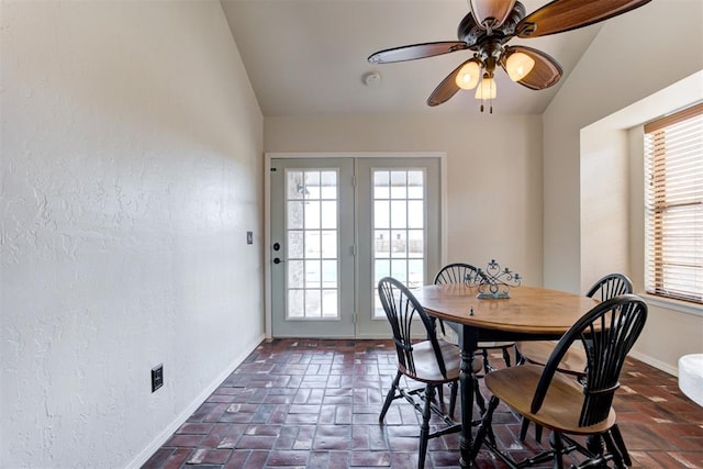 dining room featuring brick floor, lofted ceiling, ceiling fan, and baseboards