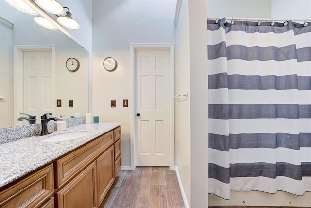 bathroom featuring baseboards, wood finished floors, and vanity