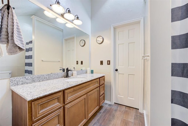 full bathroom featuring curtained shower, vanity, baseboards, and wood finished floors