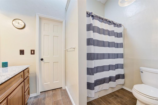 bathroom with baseboards, toilet, a shower with curtain, vanity, and wood finish floors