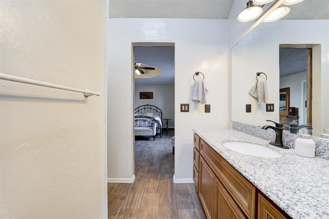 ensuite bathroom featuring ensuite bathroom, vanity, a textured ceiling, wood finished floors, and baseboards