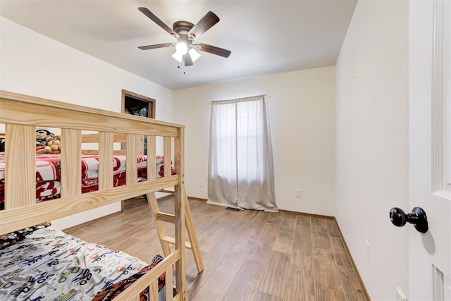 bedroom featuring baseboards, visible vents, a ceiling fan, and wood finished floors